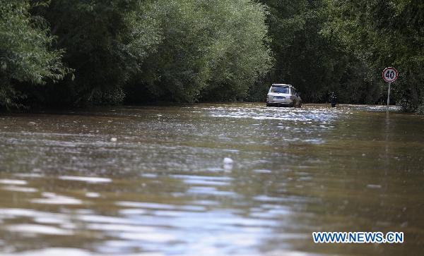 A vehicle moves slowly on a flood ravaged road linking Lhasa and Quxu County in Tibet Autonomous Region on July 30, 2010. Five kilometers of the road was covered by flood water caused by heavy rains, which caused a traffic jam. The road is also the only way for people to get to Gonggar airport in Lhasa.