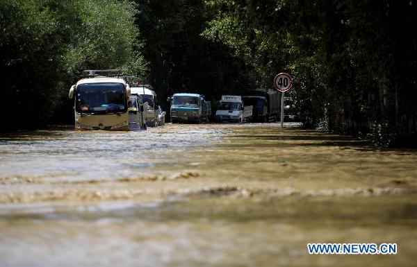 Vehicles move slowly on a flood ravaged road linking Lhasa and Quxu County in Tibet Autonomous Region on July 30, 2010. Five kilometers of the road was covered by flood water caused by heavy rains, which caused a traffic jam. The road is also the only way for people to get to Gonggar airport in Lhasa.