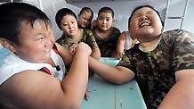 Two boys hand-wrestle during a break at the training camp in Shenyang, capital of northeast China's Liaoning Province on July 29, 2010.