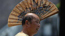 A man uses the fan as a sunshade as he walks at the Renmin Square in Chongqing, southwest China, July 29, 2010.