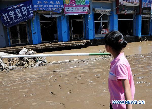 A girl looks at a flood-ravaged street in Kouqian Township of Yongji County, northeast China's Jilin Province, July 29, 2010.
