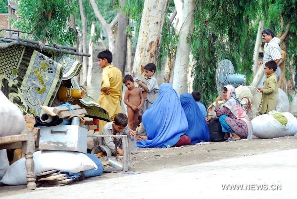 People migrate with their belongings as their houses were flooded following heavy monsoon rains in northwest Pakistan&apos;s Peshawar, on July 30, 2010. At least 420 people were killed in the flood-hit Khyber Pakhtunkhwa province in northwest Pakistan, said the Pakistani interior minister Rehman Malik on Friday. 