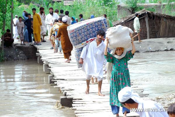 People migrate with their belongings as their houses were flooded following heavy monsoon rains in northwest Pakistan&apos;s Peshawar, on July 30, 2010. At least 420 people were killed in the flood-hit Khyber Pakhtunkhwa province in northwest Pakistan, said the Pakistani interior minister Rehman Malik on Friday.