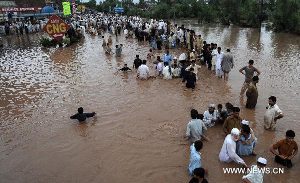 People migrate as their houses were flooded following heavy monsoon rains in northwest Pakistan&apos;s Peshawar, on July 30, 2010. At least 420 people were killed in the flood-hit Khyber Pakhtunkhwa province in northwest Pakistan, said the Pakistani interior minister Rehman Malik on Friday.