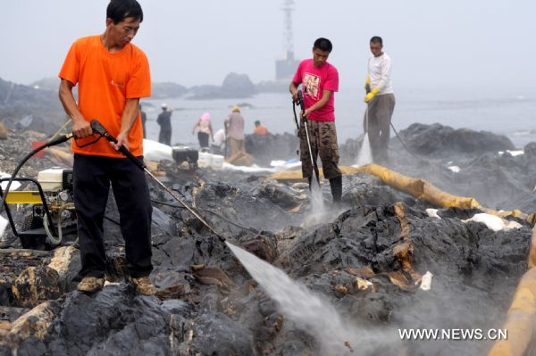 Workers clean the reefs at Xieziwan bay in Dalian, northeast China&apos;s Liaoning Province, July 30, 2010. Industrial cleaners and gas welding blowpipes were devoted to clean the reefs after the oil pipe explosion at Dalian Xingang Harbor. (Xinhua/Ma Yidong) (ly) 