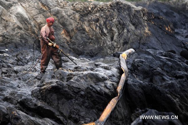 A worker cleans the reefs at Xieziwan bay in Dalian, northeast China&apos;s Liaoning Province, July 30, 2010. Industrial cleaners and gas welding blowpipes were devoted to clean the reefs after the oil pipe explosion at Dalian Xingang Harbor. (Xinhua/Ma Yidong) (ly) 