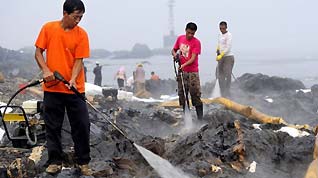 Workers clean the reefs at Xieziwan bay in Dalian, northeast China's Liaoning Province, July 30, 2010. Industrial cleaners and gas welding blowpipes were devoted to clean the reefs after the oil pipe explosion at Dalian Xingang Harbor.