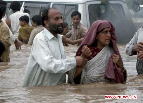 People walk through the waterlogged street in northwest Pakistan&apos;s Pabbi on Aug. 1, 2010. 