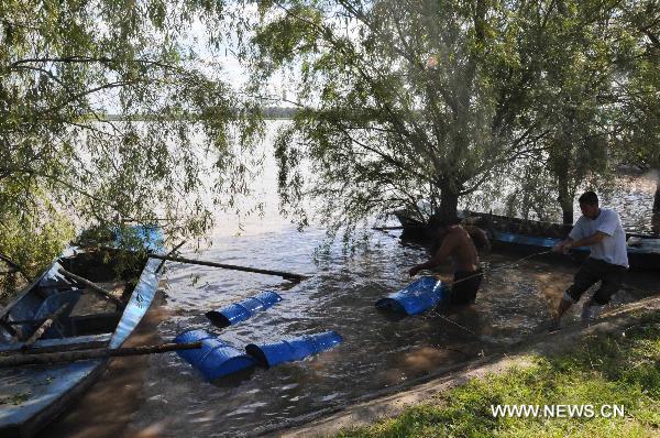 Local residents retrieve chemical containers from Songhua River at the Wukeshu Town in Yushu City, northeast China's Jilin Province, Aug. 1, 2010.