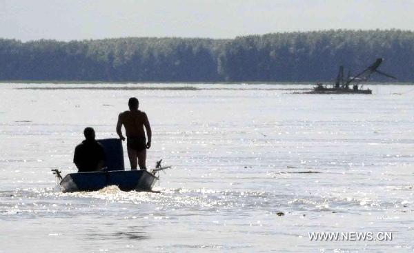 Local residents carry chemical containers from Songhua River at the Wukeshu Town in Yushu City, northeast China's Jilin Province, Aug. 1, 2010. 