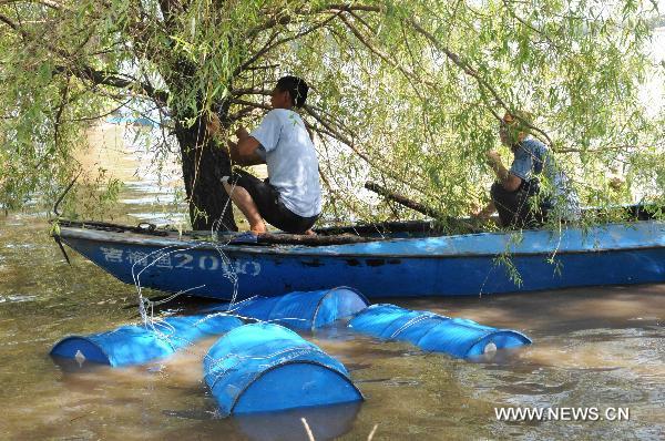 Local residents retrieve chemical containers from Songhua River at the Wukeshu Town in Yushu City, northeast China's Jilin Province, Aug. 1, 2010.