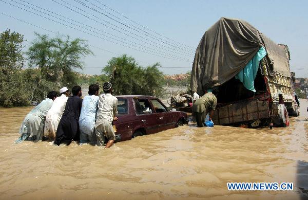 People push vehicles through the waterlogged street in northwest Pakistan's Risalpur on August 2, 2010.