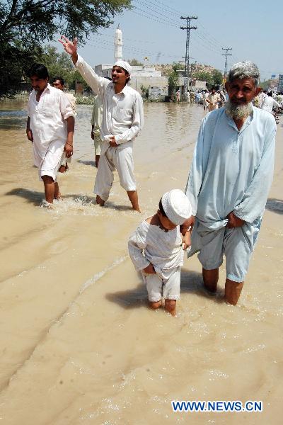 People walk through the waterlogged street in northwest Pakistan's Risalpur on August 2, 2010. 