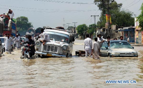 People push vehicles through the waterlogged street in northwest Pakistan's Risalpur on August 2, 2010.