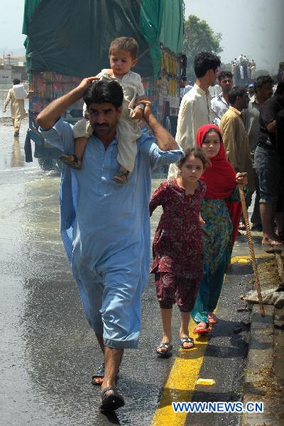 People walk through the waterlogged street in northwest Pakistan's Risalpur on August 2, 2010. 