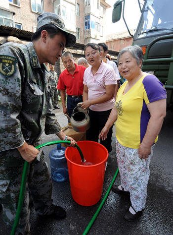 Residents wait for drinking water in Tonghua, Jilin province August 2. Torrential rain has damaged water pipelines in the city, leaving 330,000 people without tap water. To relief the water shortage, fire trucks and temporary water supply stations provide water to residential communities in the city every day. [Xinhua]
