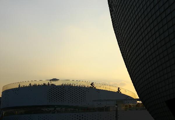 Photo taken on Aug. 1, 2010 shows part of the Finland Pavilion with the Denmark Pavilion on which several bicyclists are riding in the background at the 2010 World Expo in Shanghai, east China.