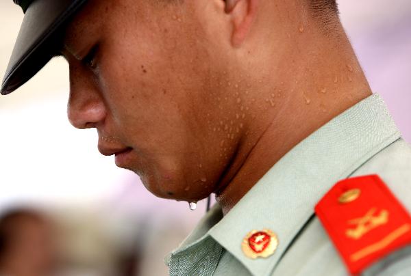 Li Shenghui, a guard at the World Expo Park, stands in the sun outside the UK Pavilion in Shanghai, east China, Aug. 3, 2010.