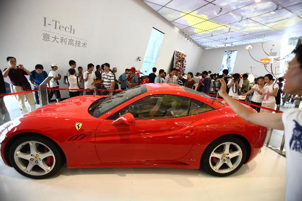 Tourists look at a Ferrari sports car in the Italy Pavilion in the World Expo Park in Shanghai, east China, Aug. 3, 2010.