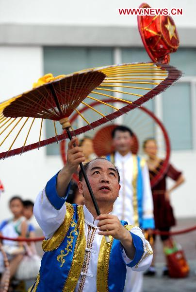 A folk artist performs with an umbrella in Shanghai, east China, Aug. 4, 2010.