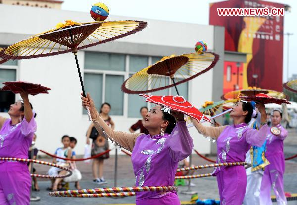 Folk artists perform with umbrellas in Shanghai, east China, Aug. 4, 2010.