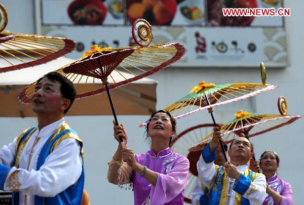 Folk artists perform with umbrellas in Shanghai, east China, Aug. 4, 2010. 