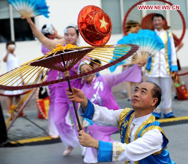 A folk artist performs with an umbrella in Shanghai, east China, Aug. 4, 2010.