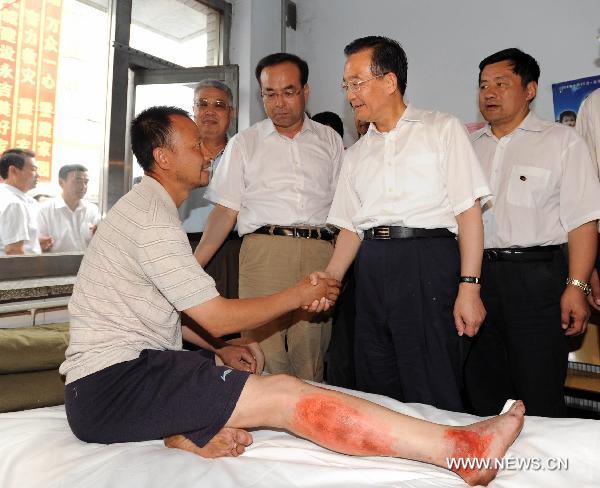 Chinese Premier Wen Jiabao (2nd R), who is also a member of the Standing Committee of the Political Bureau of the Communist Party of China Central Committee, shakes hands with an injured man in the flood-hit area in Yongji County of Jilin City, northeast China's Jilin Province on Aug. 3, 2010. 