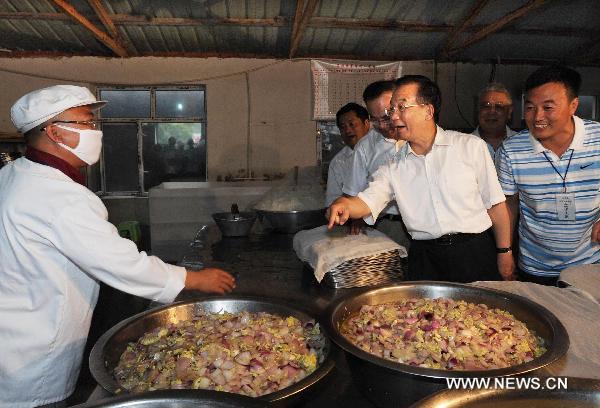 Chinese Premier Wen Jiabao (3rd R), who is also a member of the Standing Committee of the Political Bureau of the Communist Party of China Central Committee, talks with a chef preparing food for flood-affected residents in the flood-hit area in Yongji County of Jilin City, northeast China's Jilin Province on Aug. 3, 2010. 