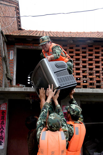 Soldiers help local villagers to move their belongings in Gulouzi township of Dandong CCity, Liaoning Province, August 4, 2010.