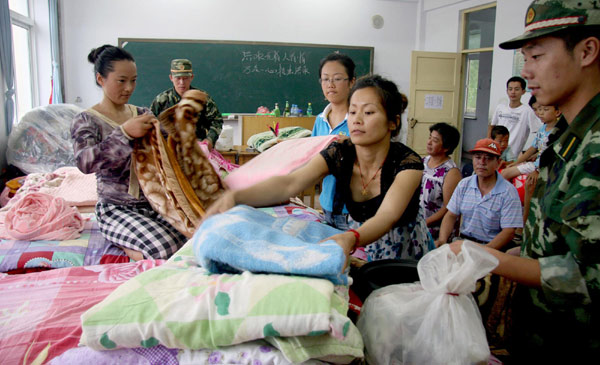 Soldiers help evacuated villagers get comfortable at a shelter in Gulouzi township of Dandong City, Liaoning Province, August 4, 2010.