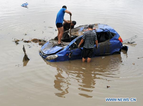 Local residents try to retrieve a car at a flood-ravaged street in Yongji County, northeast China's Jilin Province, Aug. 5, 2010. 