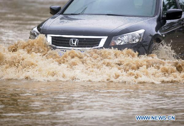 A car moves on flood-ravaged street in Jilin City, northeast China's Jilin Province, Aug. 5, 2010. Rainfall reached 204 mm over the previous 24 hours as of 8:00 AM Thursday in central Jilin, the provincial meteorological station said. 