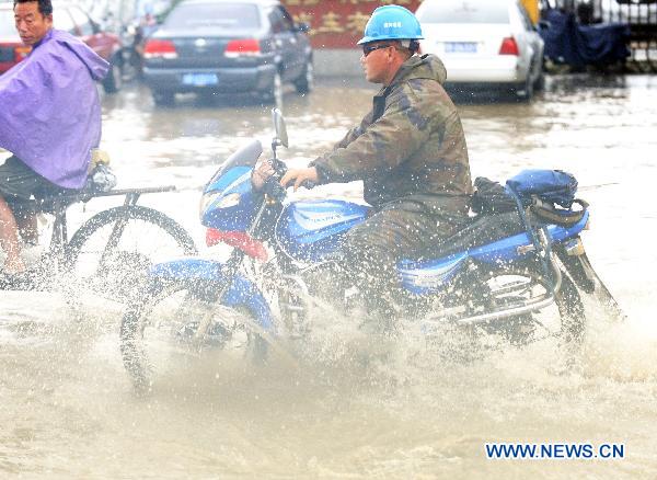 People ride a moto cycles on flood-ravaged street in Jilin City, northeast China's Jilin Province, Aug. 5, 2010. 