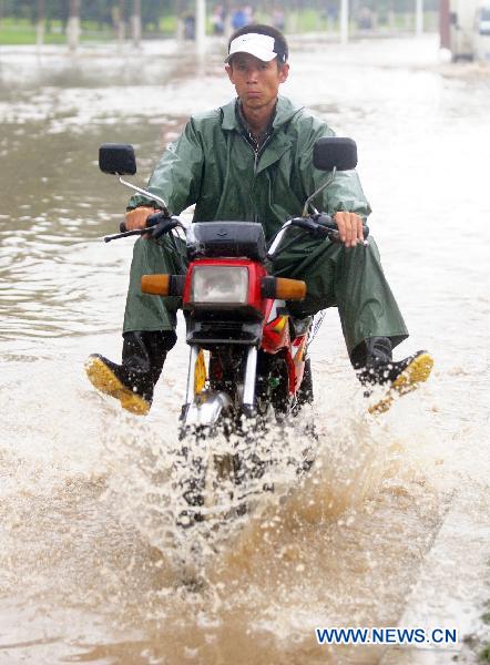 A man rides a moto cycle on flood-ravaged street in Jilin City, northeast China's Jilin Province, Aug. 5, 2010.