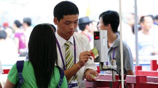 A staff member of China Pavilion helps a visitor pass the entrance with her electronic reservation ticket in the Shanghai World Expo Park in Shanghai, east China, Aug. 6, 2010. Electronic reservation tickets are taken test application in China Pavilion on Friday.
