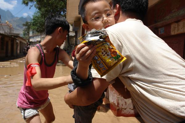 Local people try to evacuate a child to safe places at Zhouqu County, Gannan Tibetan Autonomous Prefecture in northwest China's Gansu Province, Aug. 8, 2010.