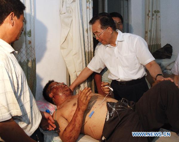 Chinese Premier Wen Jiabao(R) visits an injured person who got hurt during the landslides at a hospital in Zhouqu County, Gannan Tibetan Autonomous Prefecture in northwest China's Gansu Province, Aug. 8, 2010. 