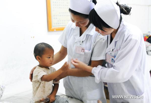 Medical staff members take care of a child saved from rain-triggered landslides in Zhouqu County of Gannan Tibetan Autonomous Prefecture, northwest China's Gansu Province, Aug. 8, 2010. 