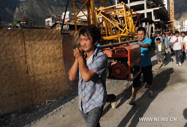 Local residents carry rescue equipment in landslide-hit Zhouqu County, Gannan Tibetan Autonomous Prefecture in northwest China's Gansu Province, Aug. 8, 2010.