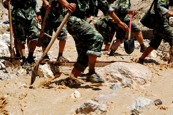 Rescue workers wade through sludge during rescue operations in mudslide-hit Zhouqu County, northwest China&apos;s Gansu Province, Aug 9, 2010.