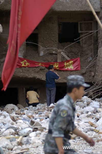 A soldier walks by a house debris in landslides-hit Zhouqu County, Gannan Tibetan Autonomous Prefecture in northwest China&apos;s Gansu Province, Aug. 9, 2010.