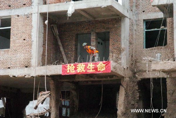 A rescuer checks a house debris in landslides-hit Zhouqu County, Gannan Tibetan Autonomous Prefecture in northwest China&apos;s Gansu Province, Aug. 9, 2010. 