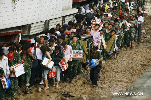 Rescuers transport relief materials on a street torn by mudslide in landslides-hit Zhouqu County, Gannan Tibetan Autonomous Prefecture in northwest China's Gansu Province, Aug. 9, 2010. 