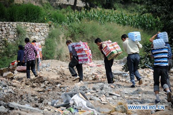 Residents of Yuanyue Village carry home relief materials in the landslides-hit Zhouqu County, Gannan Tibetan Autonomous Prefecture in northwest China's Gansu Province, Aug. 10, 2010.