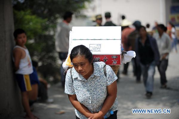 A woman carries home relief materials in the landslides-hit Zhouqu County, Gannan Tibetan Autonomous Prefecture in northwest China's Gansu Province, Aug. 10, 2010.