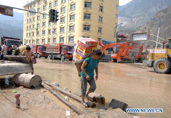 A woman carries home relief materials in the landslides-hit Zhouqu County, Gannan Tibetan Autonomous Prefecture in northwest China's Gansu Province, Aug. 10, 2010. 