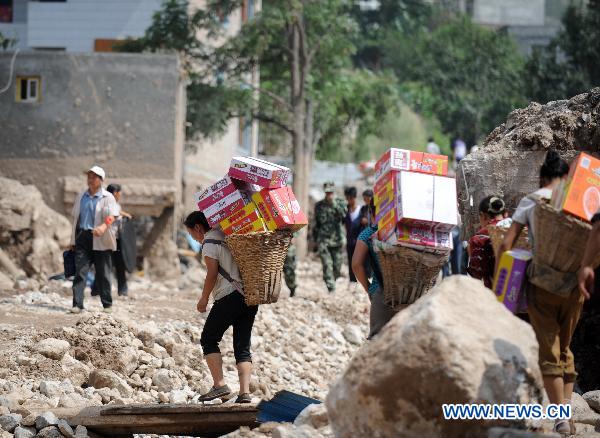 Residents of Yuanyue Village carry home relief materials in the landslides-hit Zhouqu County, Gannan Tibetan Autonomous Prefecture in northwest China's Gansu Province, Aug. 10, 2010. 