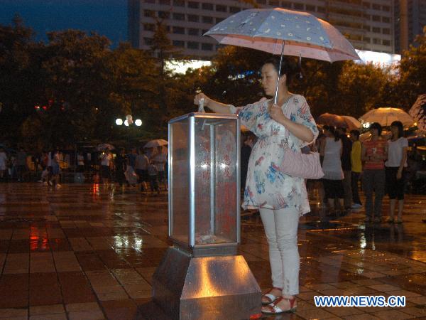 A woman donates for the mudslides-hit Zhouqu County at Dongfanghong Square in Lanzhou, capital of Gansu Province, Aug. 10, 2010.