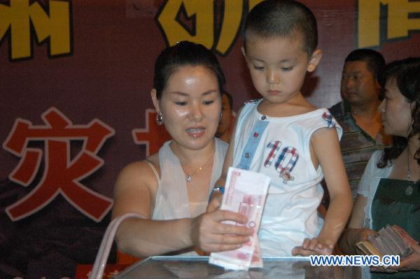 A woman donates for the mudslides-hit Zhouqu County at Dongfanghong Square in Lanzhou, capital of Gansu Province, Aug. 10, 2010.